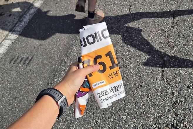 떨어져나가버린 배번표 배번표 모서리 4곳을 옷핀으로 상의에 고정했지만 배번표가 땀에 녹아 떨어져버리는 바람에 들고 뛸 수 밖에 없었다.