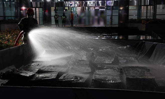 27일 밤 대전 유성구 국가정보자원관리원 화재 현장에서 한 소방대원이 불에 탄 리튬이온 배터리를 담은 소화수조에 물을 뿌리고 있다. 연합뉴스