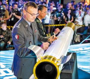 지난달 2일 폴란드 키엘체 국제 방위산업 전시회(MSPO 2025)에서 열린 천무 유도탄 생산을 위한 합작법인 계약식에서 한국과 폴란드 양국 정부·군·업계 관계자들은 성공적인 방산협력을 축하하며 천무 모형탄에 서명하고 있다. 한화에어로스페이스 제공