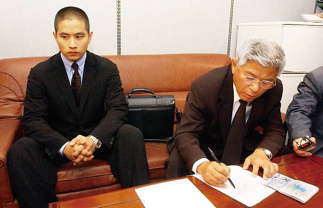 2003년 입국 금지 조치가 일시 해제된 유승준이 법무부 출입국관리사무소에서 입국신청서를 작성하고 있다. 오른쪽은 유씨의 부친 ⓒ연합뉴스
