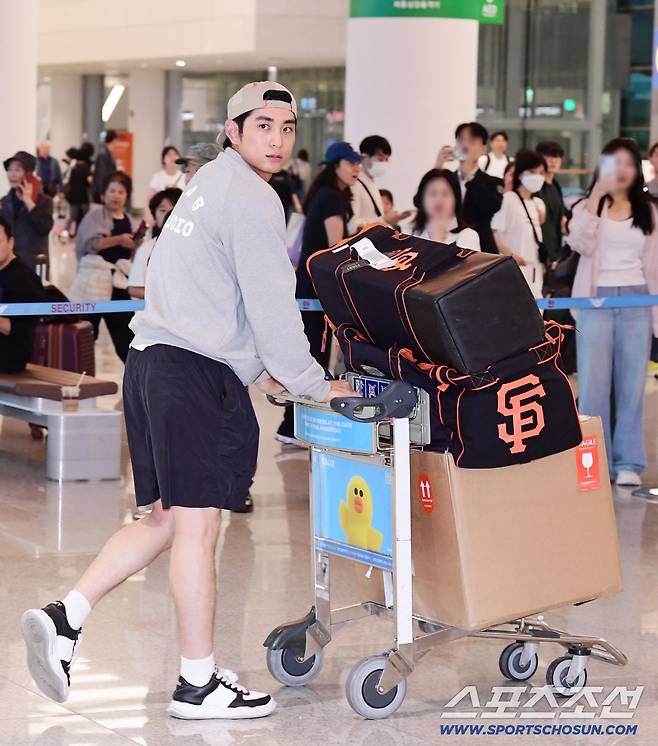 팬들이 지켜보는 가운데 입국장을 나서고 있는 이정후.