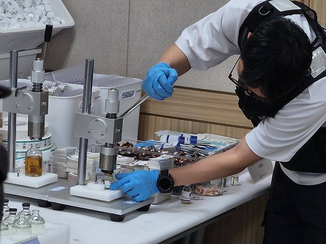 식품의약품안전처 특별사법경찰이 압류한 물품으로 무허가 의약품 제조 과정을 시연하고 있다. 뉴시스