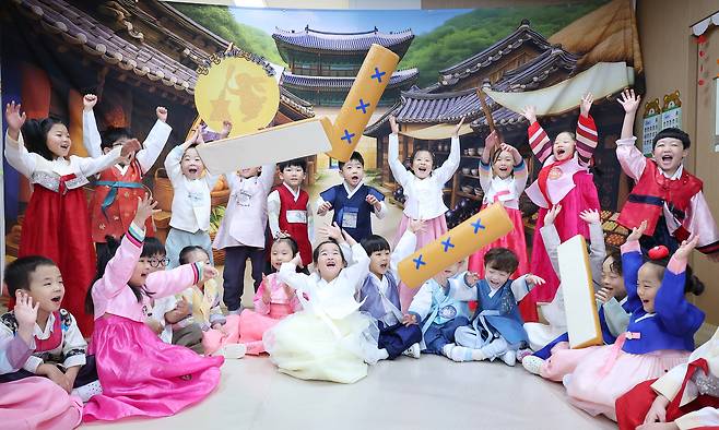 Children dressed in hanbok play yutnori, a traditional Korean game often played during the holiday, at a day care center in Busan on Wednesday. (Yonhap)