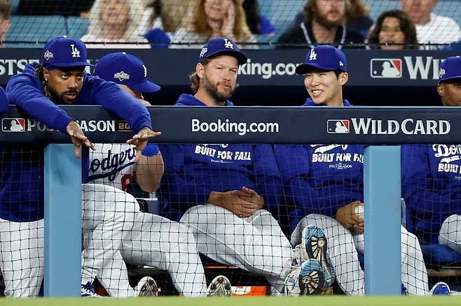 김혜성(오른쪽)이 1일 열린 메이저리그 내셔널리그 와일드카드 시리즈 1차전 도중 더그아웃에서 클레이턴 커쇼(가운데)와 이야기를 나누며 미소짓고 있다. AFP연합뉴스