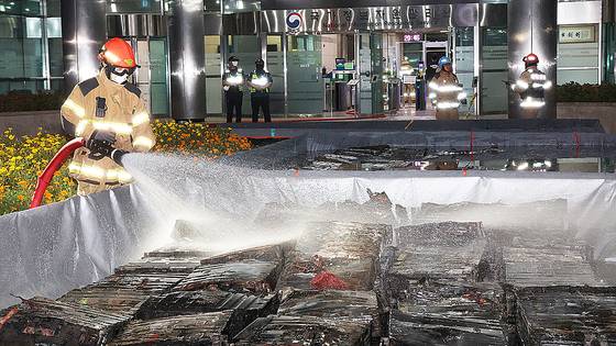 지난달 27일 밤 대전 유성구 국가정보자원관리원 화재 현장에서 소화수조에 담긴 불에 탄 리튬이온 배터리에 소방대원이 물을 뿌리고 있다. 연합뉴스