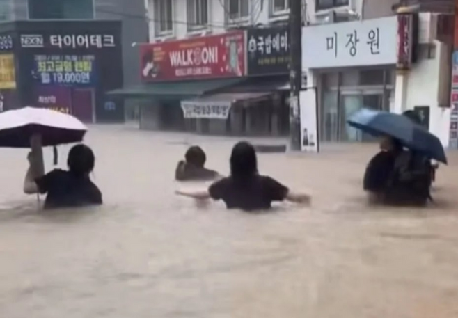 광주광역시에 국지성 집중호우 피해가 잇따른 가운데, 시민들이 허리까지 찬 빗물을 헤치고 길을 건너고 있다.[X(구 트위터) 갈무리]