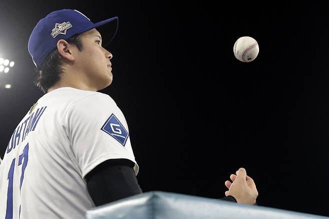 LA 다저스 오타니 쇼헤이가 지난 2일(한국시각) 다저스타디움에서 열린 신시내티 레즈와의 와일드카드 시리즈 2차전서 8회 수비 때 공을 만지작거리며 경기를 보고 있다. AFP연합뉴스