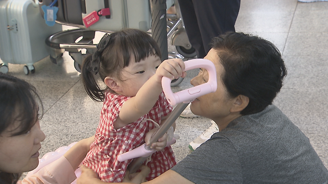 도착장 바닥에 앉아 손녀와 시간을 보내는 할머니.