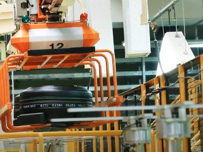 넥센타이어 창녕공장에서 성형 공정을 마친 '그린 타이어'가 '전동화 모노레일 시스템'(EMS)에 실려 운반되는 모습. 모노레일 위 대차는 그린 타이어를 가류 공정 기계까지 자동으로 운반한다(창녕공장 홍보영상 갈무리). 2025.09.26.