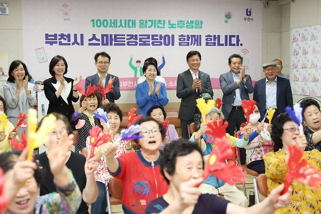 조용익(맨 뒤 왼쪽서 5번째) 부천시장이 7월 이재명 정부 국정기획위원회 AI TF 위원들과 스마트 경로당인 부천소새울경로당을 찾아 프로그램을 참관하며 박수를 치고 있다. (사진 = 부천시 제공)