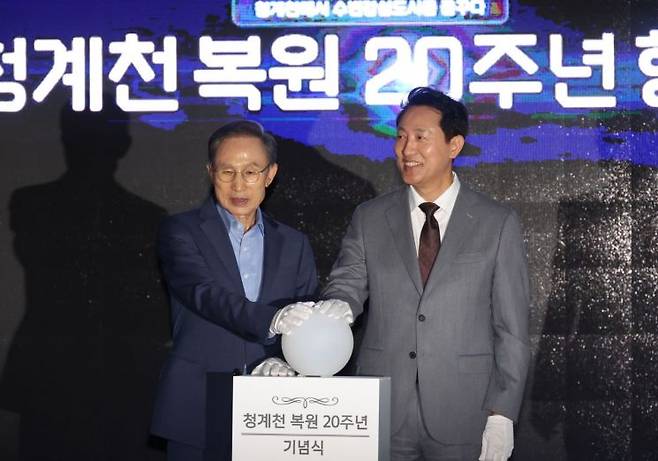 이명박 전 대통령과 오세훈 서울시장이 1일 청계광장에서 열린 ‘청계천 복원 20주년 행사’에서 새로운 공공미술 작품의 점등 버튼을 누르고 있다. 연합뉴스