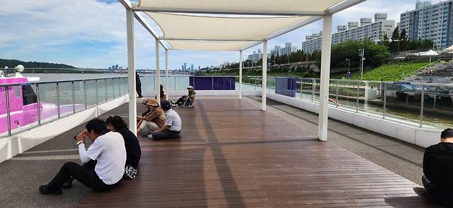 한강버스 마곡선착장 2층의 모습. 평상에 시민들이 앉아서 휴식을 취하고 있다.