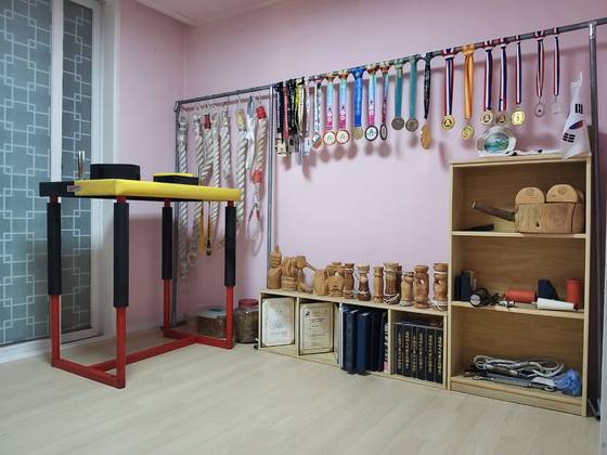 팔씨름 선수로 활동하는 경남 김해시청 공원과 실무관 서상진(55)씨 자택에 그간 팔씨름 대회에서 수상한 메달과 직접 만든 팔씨름 훈련용 손잡이 등이 진열돼 있다. 사진 서상진씨