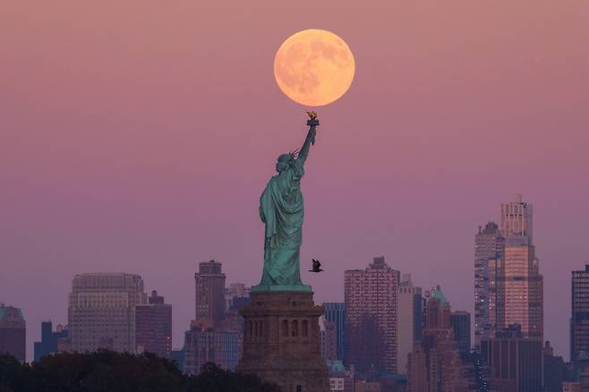 6일(현지 시각) 미국 뉴저지주 저지시티에서 자유의 여신상과 브루클린 스카이라인 뒤로 올해 첫 슈퍼문이 떠오르고 있다./AP 연합뉴스