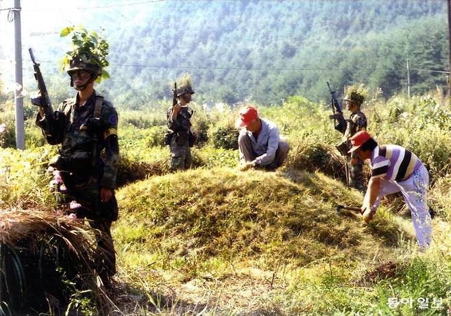추석 연휴를 이틀 앞두고 강릉시 강동면 임곡리 무장간첩 수색 작전 지역 내에서 군인들이 경계근무를 하는 가운데 주민들이 벌초 작업을 하고 있다. 동아일보 DB