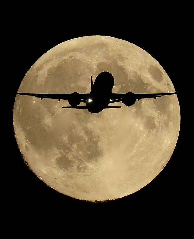 6일(현지시간) 영국 런던 상공을 비행하던 여객기가 올해 첫 슈퍼문인 ‘하베스트 문(추수달)’ 앞을 지나고 있다. 로이터 연합