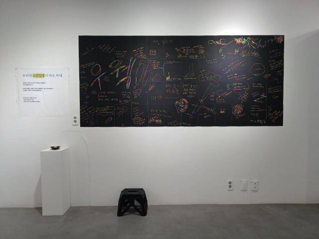 ▲세 번째 섹션 "우리가 느낀 감정이 바로 피해"는 검은 벽을 긁어내면 무지개빛을 낸 메시지가 드러나도록 관람객 참여를 유도하고 있다.