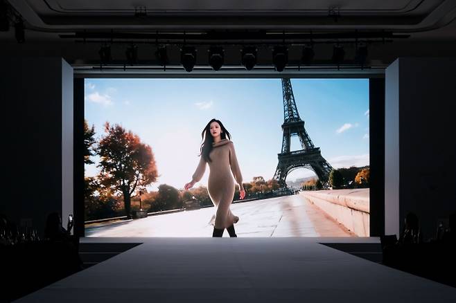 KT알파 쇼핑의 2025년 FW 패션 쇼케이스 현장에서 AI 모델이 에펠탑 앞을 걸어가고 있다. KT알파 쇼핑 제공