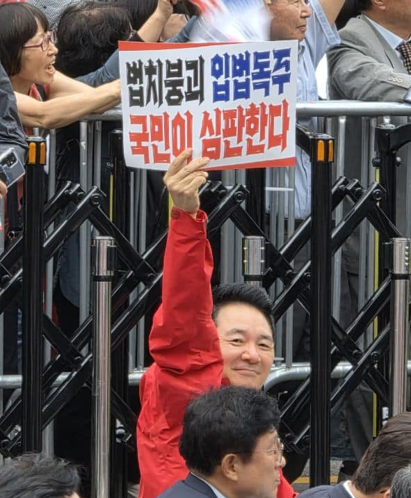 윤석열 정부 대통령실 미래전략기획관을 지낸 장성민 국민의힘 전 의원이 지난 9월 28일 서울 숭례문 인근에서 국민의힘이 개최한 이재명 정부 규탄 집회에 참여한 와중 ‘법치붕괴 입법독주 국민이 심판한다’라고 적힌 손팻말을  들어보이고 있다.<장성민 전 국회의원 페이스북 사진>