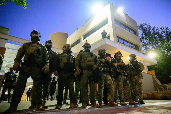 국토안보부, 국경순찰대 등 연방 요원들이 6일(현지시간) 오리건주 포틀랜드 시내에 있는 이민세관단속국(ICE) 시설 밖에서 경비를 서고 있다. AFP=연합뉴스