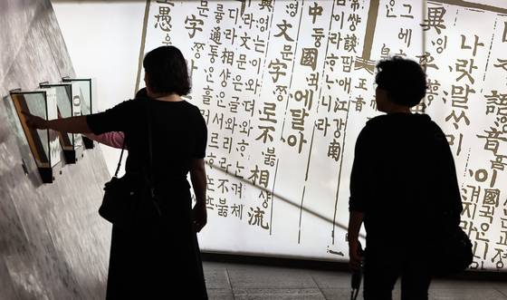 Citizens watch a multimedia video artwork about the creation of Hangul at ″The Story of King Sejong″ exhibition in Gwanghwamun, central Seoul, on Oct. 8. [NEWS1]