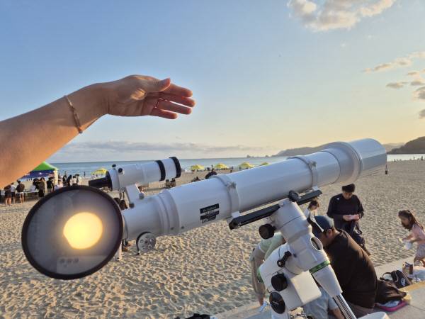 10일 오후 해운대 웨스틴 조선 호텔 뒤쪽 빌딩 숲으로 넘어가는 태양이 천체망원경 렌즈에 담기고 있다. 부산과학기술협의회 제공