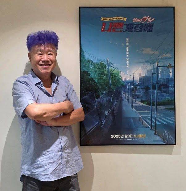 극장판 포스터 옆에서 팔짱을 낀 채 포즈를 취한 원작자 이진주 작가. NEW 제공