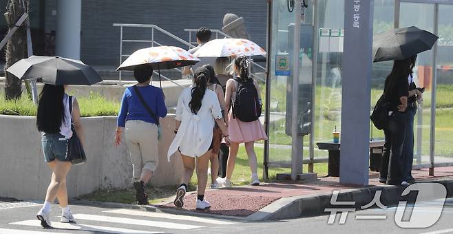 12일 오후 제주시 용담 해안도로에서 양산과 반팔 차림을 한 관광객들이 제주의 풍광을 즐기고 있다. 제주는 10월에도 낮 기온이 29~30도의 무더운 날씨를 보이고 있다. 2025.10.12/뉴스1 ⓒ News1 고동명 기자