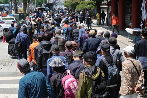 Senior citizens wait in line for free lunch in front of the Tapgol Park in Jongno District, central Seoul, on May 12. [NEWS1]