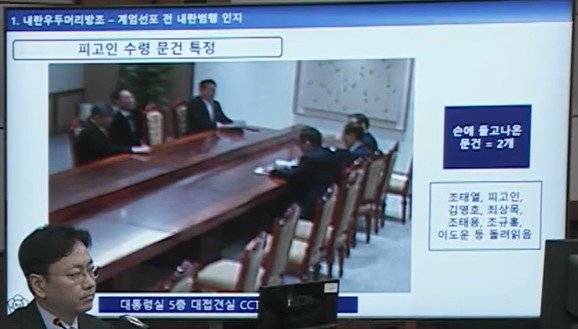 서울중앙지법 형사합의33부(부장판사 이진관) 심리로 열린 한덕수 전 국무총리 2차 공판에서 특검이 제시한 12·3 비상계엄 당일 대통령실 폐쇄회로(CC)TV 영상 화면에 한덕수 전 국무총리가 문건을 보면서 국무위원 등과 대화하는 모습이 재생되고 있다. 특검은 “한 전 총리가 대통령 집무실에서 나오면서 계엄 문건 2개를 가지고 나왔고, 이를 접견실 책상에서 일고 있는 모습”이라고 설명했다. 법원 공판 중계 화면 캡처