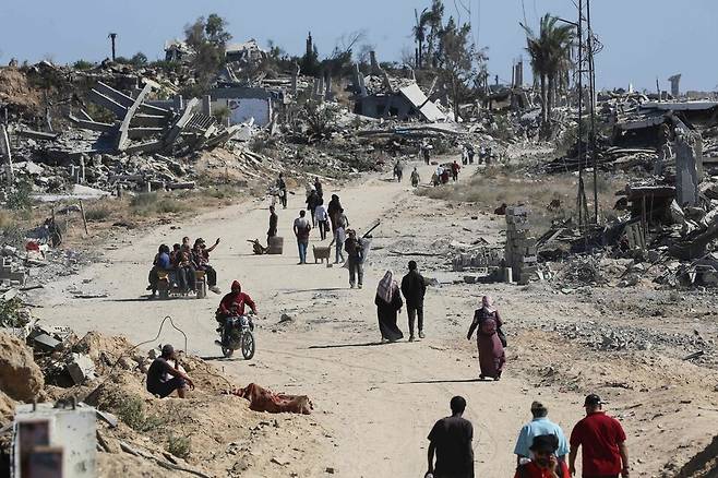 14일 팔레스타인 가자지구 중부 누세이라트 난민캠프에서 주민들이 폐허로 변한 길을 걷고 있다. AFP 연합뉴스