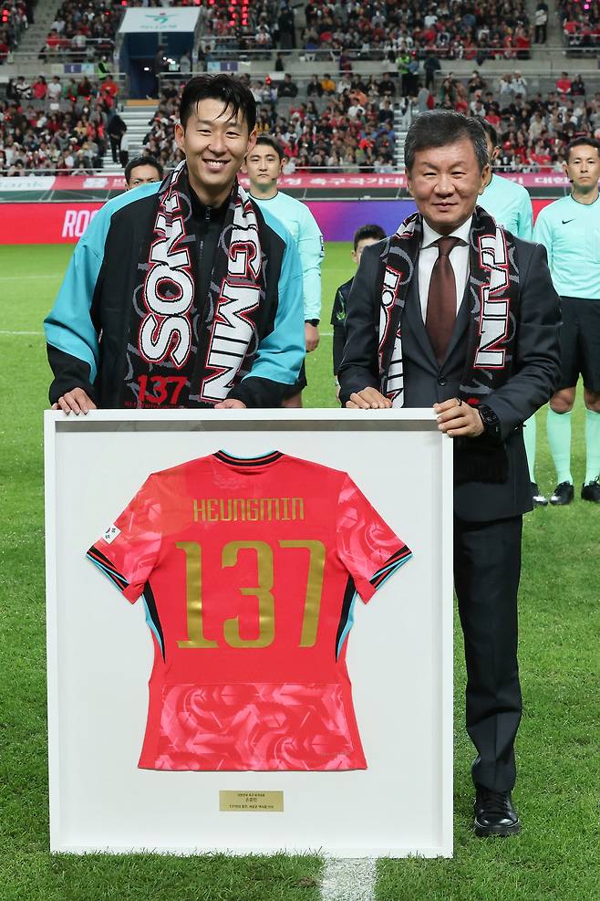 14일 서울 마포구 서울월드컵경기장에서 열린 한국과 파라과이 축구 대표팀의 친선경기.     경기 시작 전 손흥민이 A매치 역대 최다 출전 기록(137경기) 기념 유니폼을 전달받은 뒤 정몽규 대한축구협화장과 기념사진을 찍고 있다. 손흥민은 지난 브라질전 출전을 통해 A매치 통산 출전 137경기를 달성하며 한국 축구의 새 역사를 작성했다. [연합]