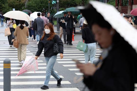 비가 내리는 14일 오전 서울 종로구 세종대로 사거리에서 우산을 든 시민들이 이동하고 있다. 뉴시스