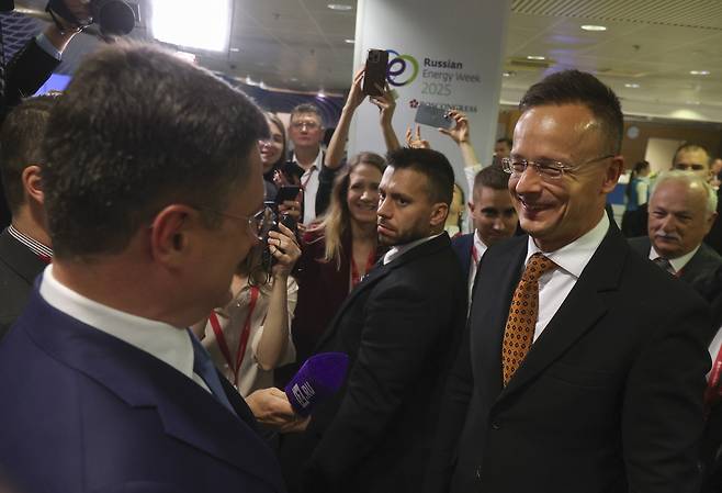페테르 씨야르토 헝가리 외무장관(오른쪽 주황색 타이)이 15일(현지시간) 러시아 모스크바에서 열린 에너지위크포럼에 참석하기 위해 이동 중 알렉산드르 노박 러 부총리와 만나 인사하고 있다. EPA연합뉴스
