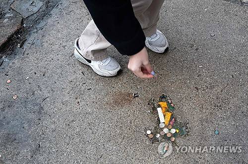 지난해 1월 한 시민이 쥐구멍에 동전을 넣고 있다 [게티이미지/AFP 연합뉴스 자료사진]