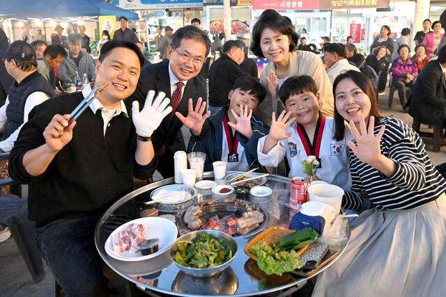 군위전통시장 야시장을 찾은 김진열 군수와 이정희 여사가 바베큐장에서 만난 젊은 가족과 기념사진을 찍었다. 군위군 제공