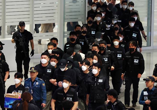 캄보디아에서 보이스피싱(전화금융사기) 등 범죄에 가담했다가 현지 경찰 조사를 받고 이민 당국에 구금됐던 한국인 64명이 18일 오전 인천국제공항 제2터미널을 통해 송환되고 있다. 공동취재사진