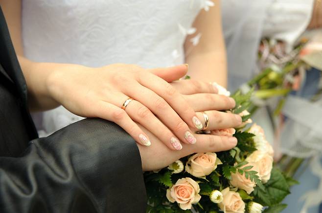 A newly married couple poses wearing wedding bands. (123rf)