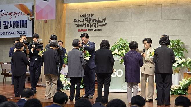 이영훈 여의도순복음교회 목사가 파주 삼마교회 30주년 감사예배에서 30년 근속자인 6명의 권사들에게 안수기도를 하고 있다.