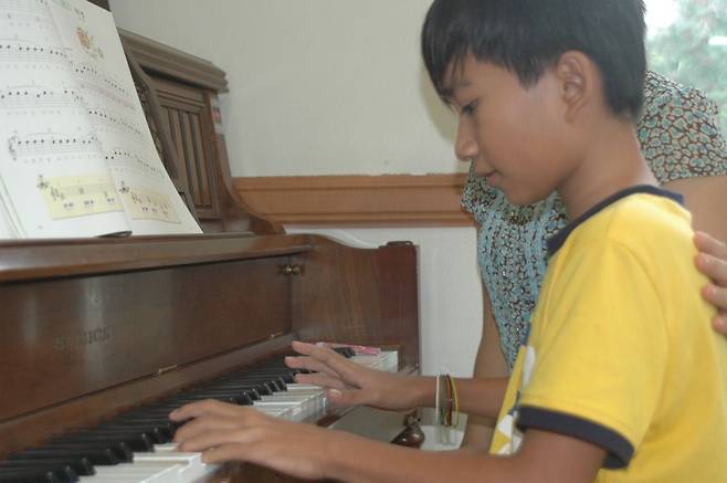 김재원 아나운서가 10여년 전 캄보디아 소년을 집으로 데려와 한 달을 보냈을 당시 모습. 피아노를 배우는 장면. 김 아나운서 제공