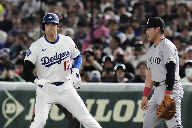<yonhap photo-5180=""> Los Angeles Dodgers' Shohei Ohtani takes a lead off of first as Yomiuri Giants' Kazuma Okamoto, right, looks on in the first inning of a spring training baseball game in Tokyo, Japan, Saturday, March 15, 2025. (AP Photo/Eugene Hoshiko)/2025-03-15 20:56:25/ <저작권자 ⓒ 1980-2025 ㈜연합뉴스. 무단 전재 재배포 금지, AI 학습 및 활용 금지></yonhap>