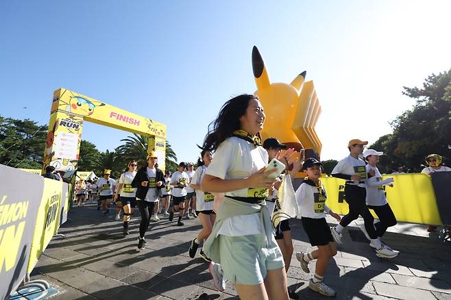 포켓몬 런에 나선 참가자들이 라인을 통과하며 활기차게 완주에 나서는 모습. (제주관광공사 제공)