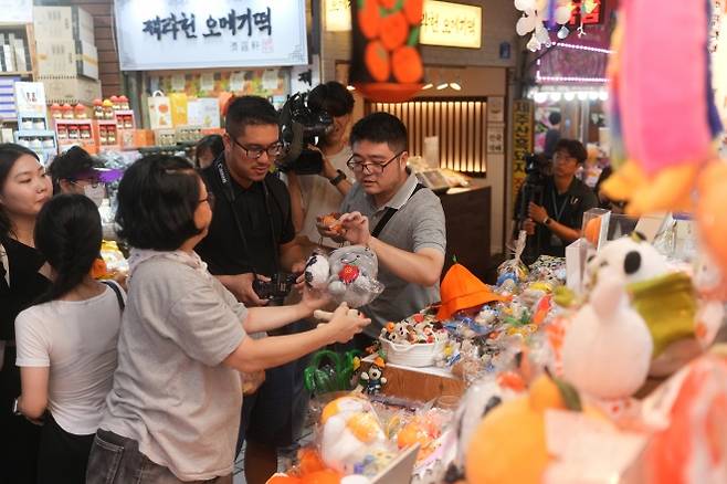 제주 동문시장을 방문한 외국인들이 제주관광 기념품을 구매하고 있다. 제주도 제공