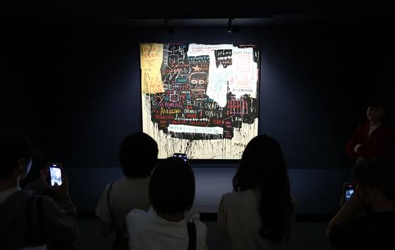 서울 동대문디자인플라자(DDP)에서 내년 1월 31일까지 열리는 ‘장 미셸 바스키아: 과거와 미래를 잇는 상징적 기호들’에 출품된 ‘미술관 경비원(브로드웨이 붕괴)’를 보는 사람들. 1983년에 그린 이 그림은 2013년 런던 크리스티 경매에서 약 172억원에 팔렸다. 김종호 기자