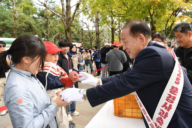 ▲ 2025 문경사과축제 대미를 장식하는 프로그램 일환으로 시민과 관광객들에게 사과를 나누어 주고 있는 신현국 문경시장.