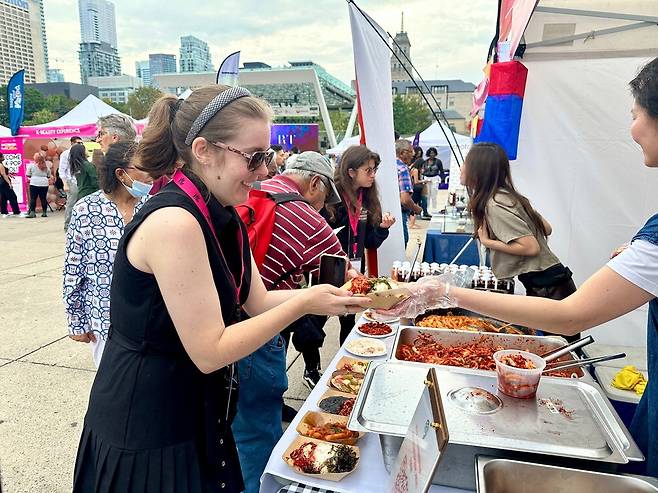 한 외국인 관광객이 길거리 음식을 건네받고 있는 모습.  한국관광공사