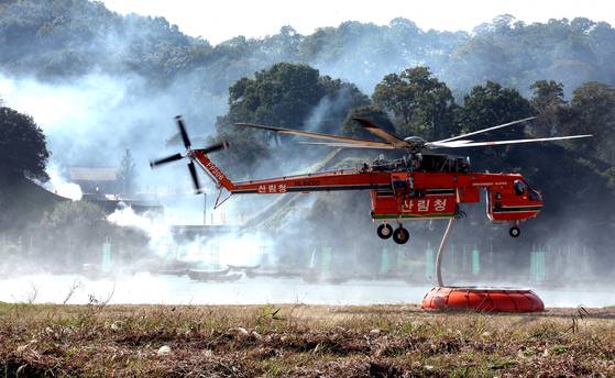지난 22일 충남 공주시 공산성 일대에서 열린 2025년 산불진화 통합훈련에서 산불진화 헬기가 이동식 저수조에서 물을 담고 있다. 연합뉴스