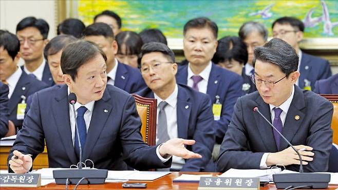 이찬진 금융감독원장(왼쪽)과 이억원 금융위원장이 27일 국회 정무위원회에서 열린 금융 부문 종합감사에서 대화하고 있다.  뉴스1