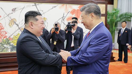 North Korean leader Kim Jong-un, left, holds hands with Chinese President Xi Jinping during their talks in Beijing on Sept. 4, in photo released by the North’s official Korean Central News Agency photo on Sept. 5. [YONHAP]
