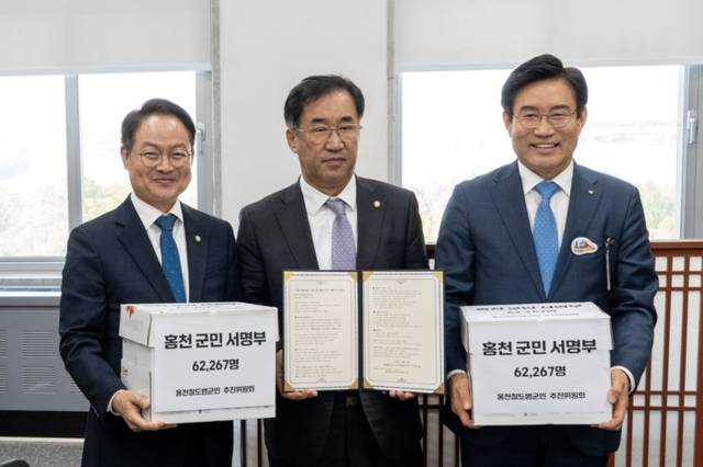 ▲ 홍천철도범군민추진위원회(위원장 이규설)는 29일 국회를 찾아 맹성규 국토교통위원장에게 용문~홍천 철도 조기 착공을 바라는 홍천군민 6만 2267명의 서명이 담긴 명부를 전달했다. 맹성규 의원실 제공.